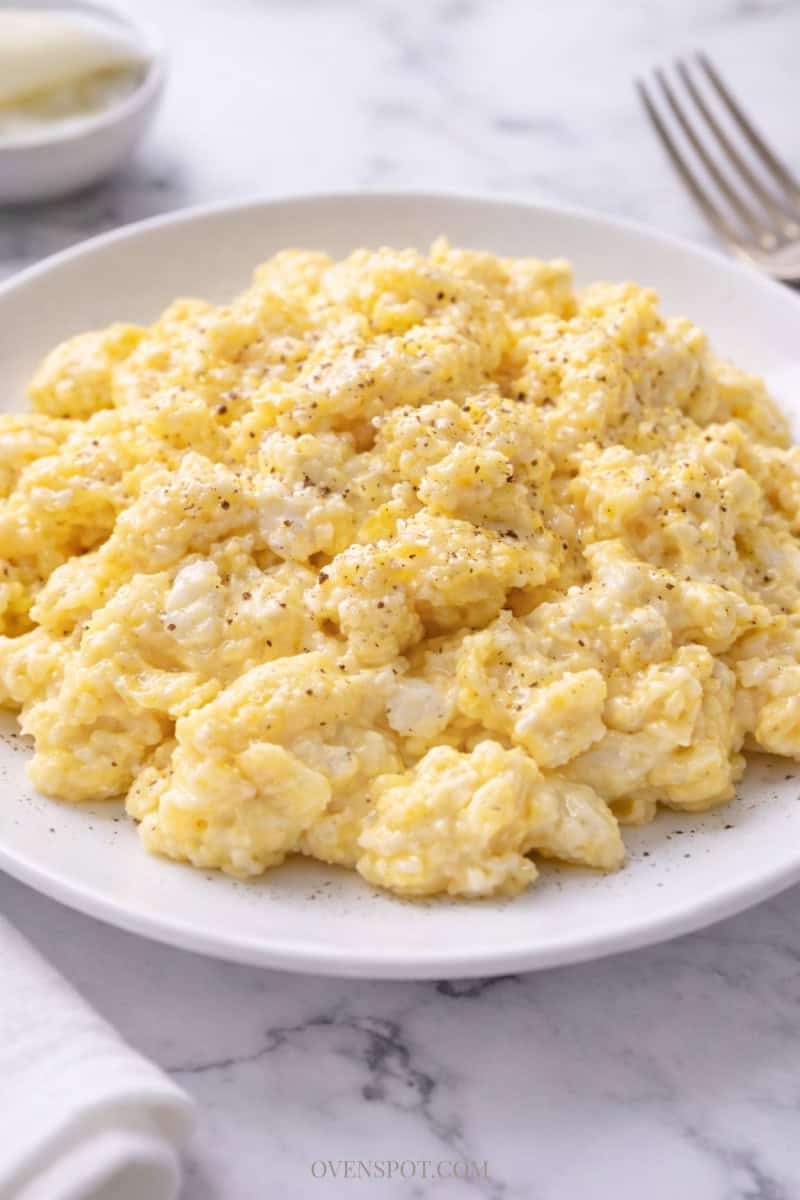 Carnivore cottage cheese scrambled eggs topped with a light sprinkle of black pepper on a white plate.