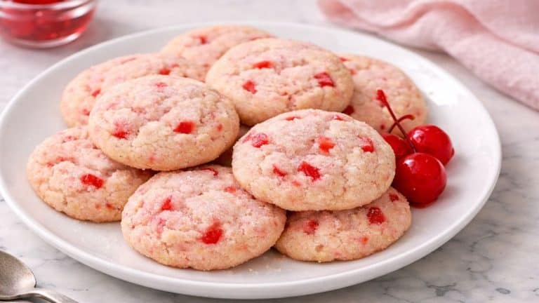 Soft maraschino cherry sugar cookies with chopped cherry pieces served on a white plate.