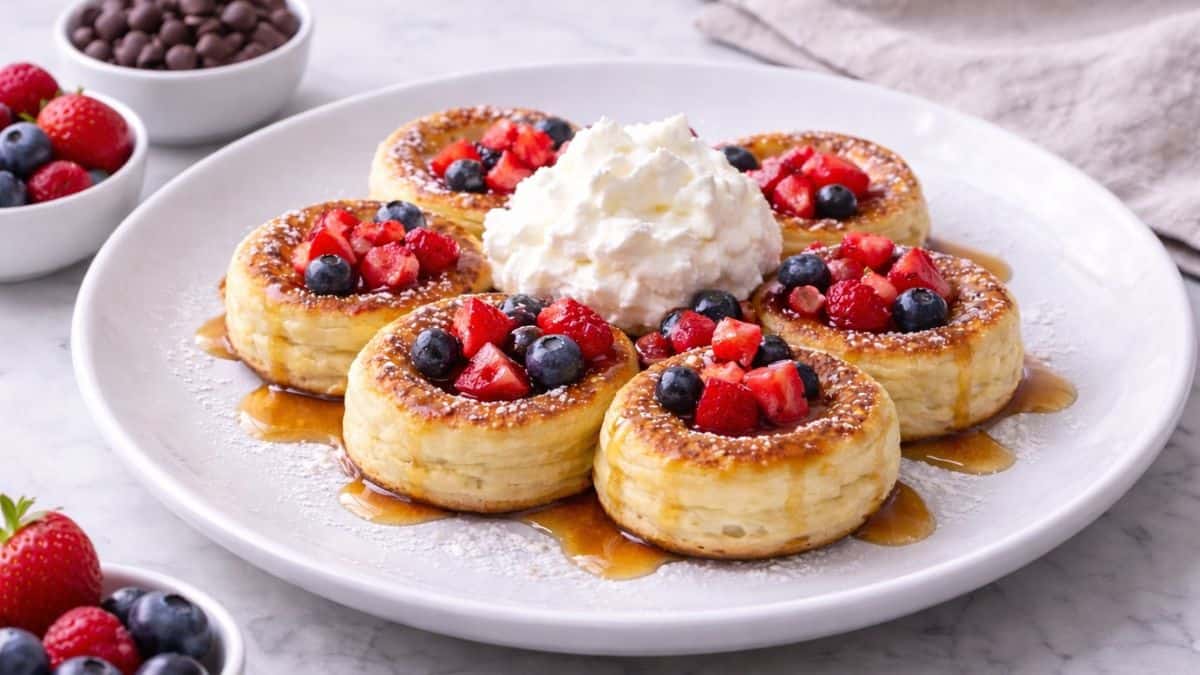 Mini German pancakes with powdered sugar, berries, maple syrup and cream.