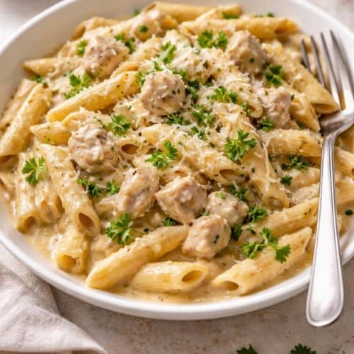 Creamy one pot chicken pasta with parsley and parmesan on a white plate.