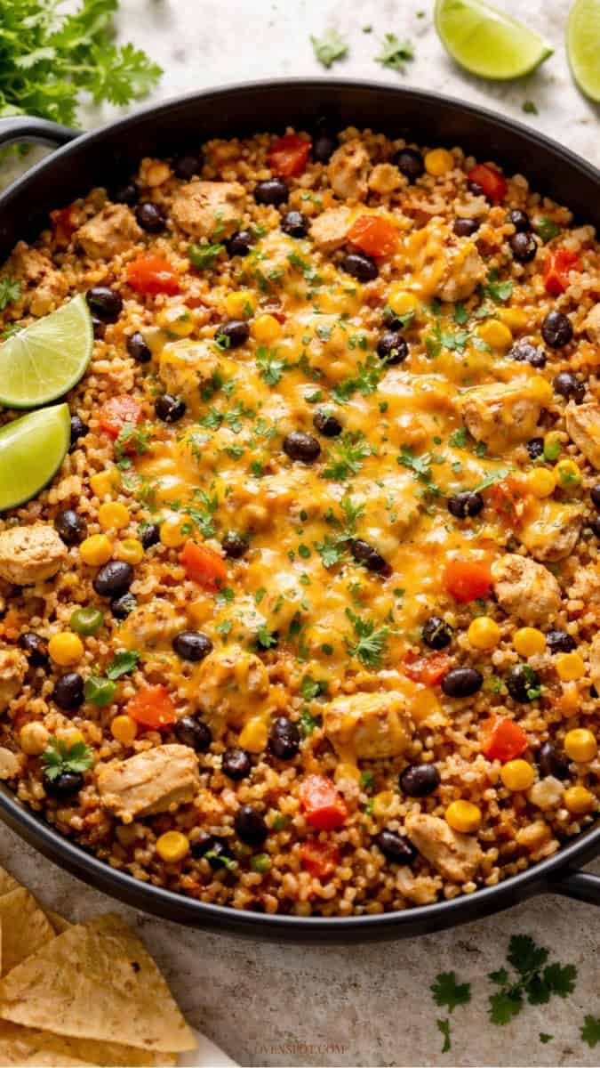 One pot chicken taco in a skillet with melted cheese, rice, black beans, and cilantro garnish.