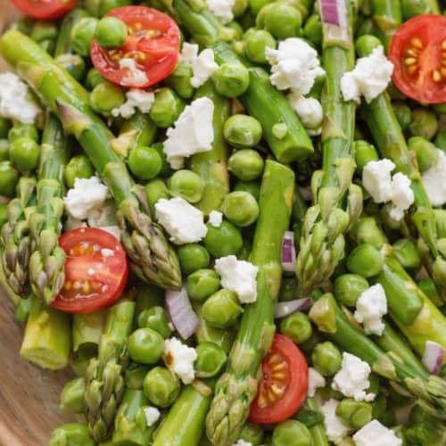 asparagus and pea salad with cherry tomatoes, red onion, and crumbled feta cheese