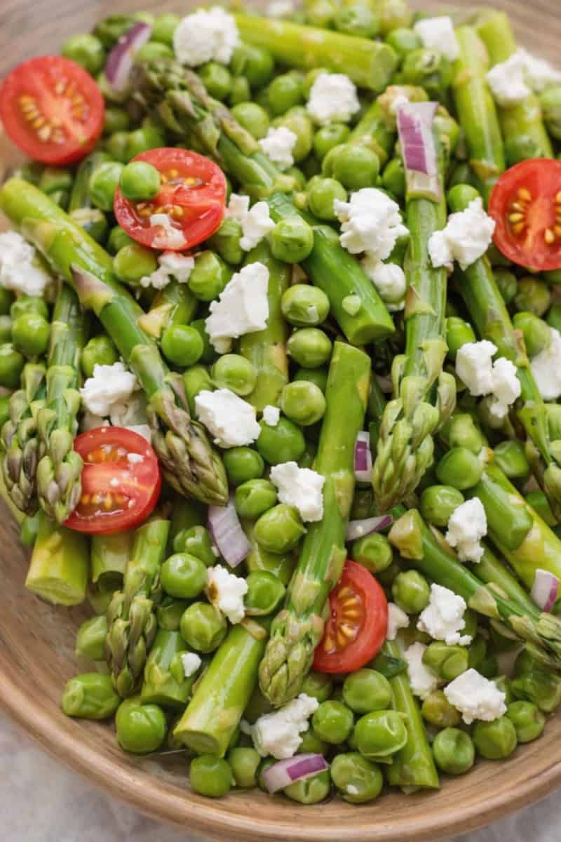 asparagus and pea salad with cherry tomatoes, red onion, and crumbled feta cheese