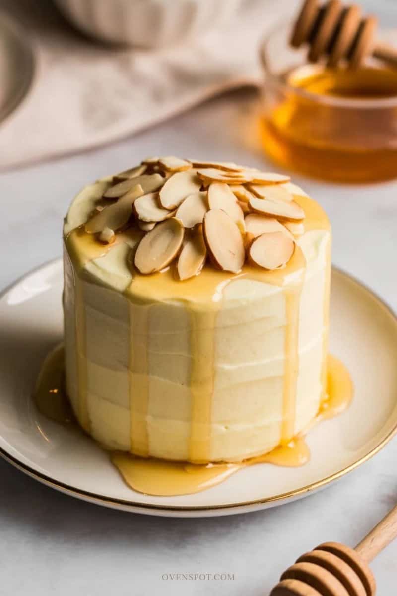 Small honey almond cake with buttercream frosting, toasted almonds, and honey drizzle