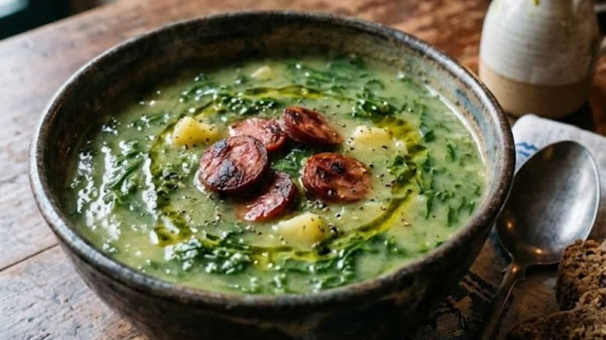 bowl of traditional Portuguese caldo verde soup with kale, potatoes, and chourico on a wooden table