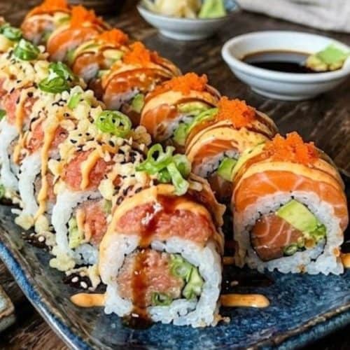 Sliced spicy tuna sushi roll on a white plate with ginger and wasabi