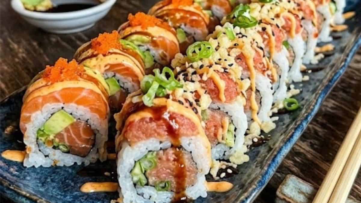 Sliced spicy tuna sushi roll on a white plate with ginger and wasabi