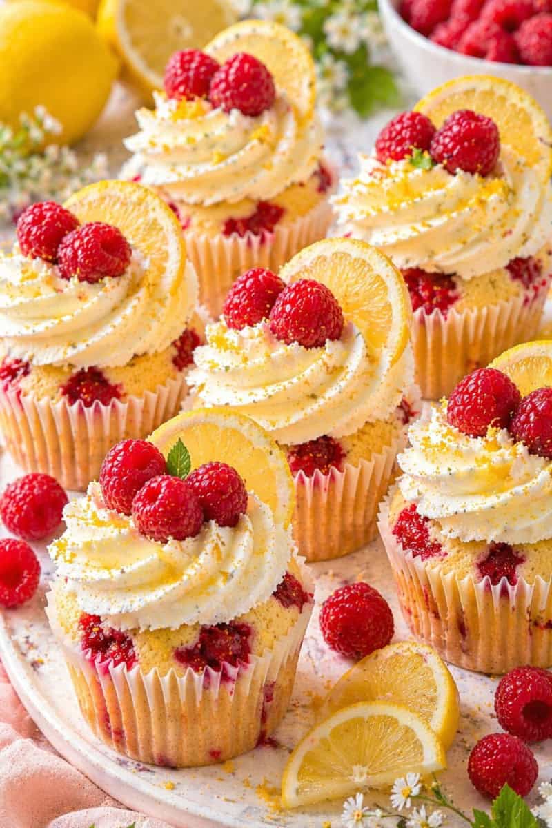 Lemon cupcakes topped with creamy frosting and fresh raspberries