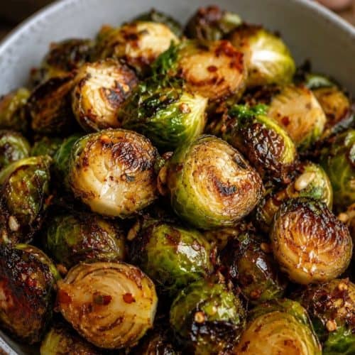 ceramic bowl filled with crispy air fryer Brussels sprouts coated in a glossy honey garlic glaze