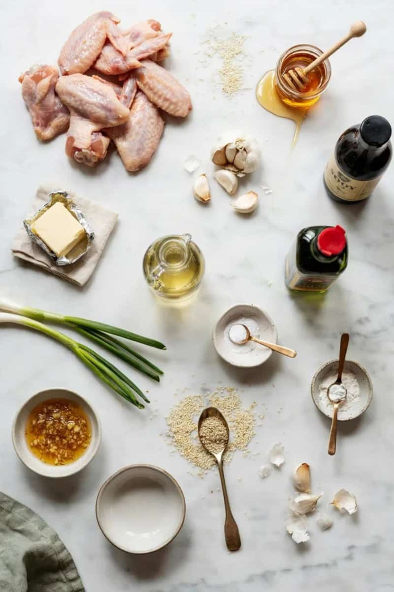 honey garlic chicken wings - chicken wings, honey, garlic cloves, soy sauce, butter, sesame oil, rice wine vinegar, baking powder, spring onions, sesame seeds, and small prep bowls