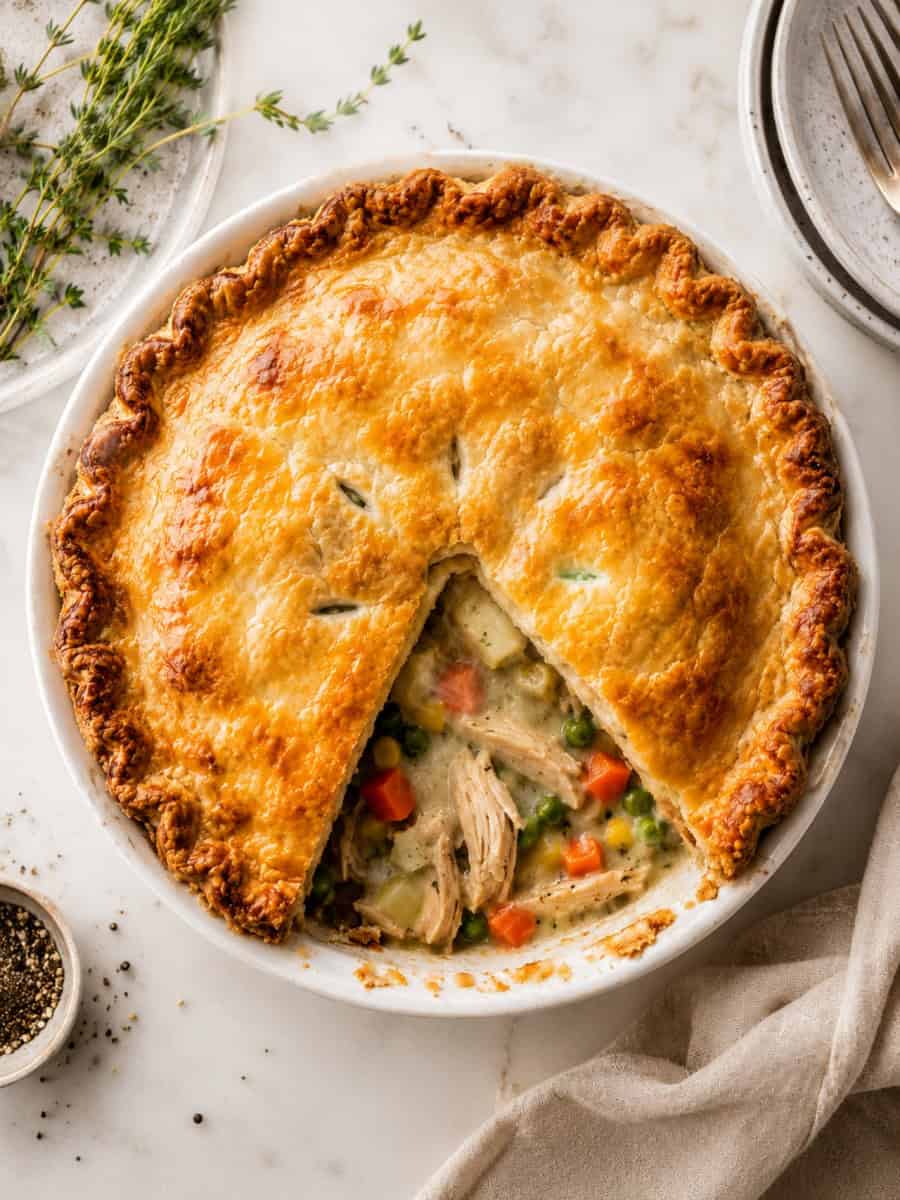 golden chicken pot pie with a flaky crust and creamy chicken and vegetable filling, served in a white pie dish